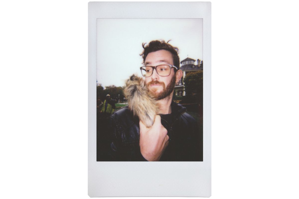 lomo instant mini film picture of a young man with glasses, holding a hairy object